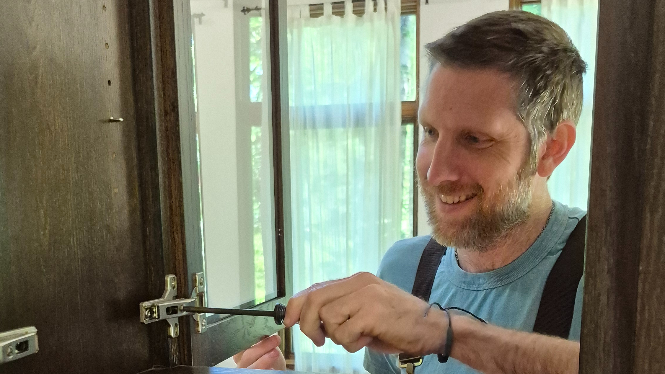Marlon with a screwdriver adjusting a cabinet door
